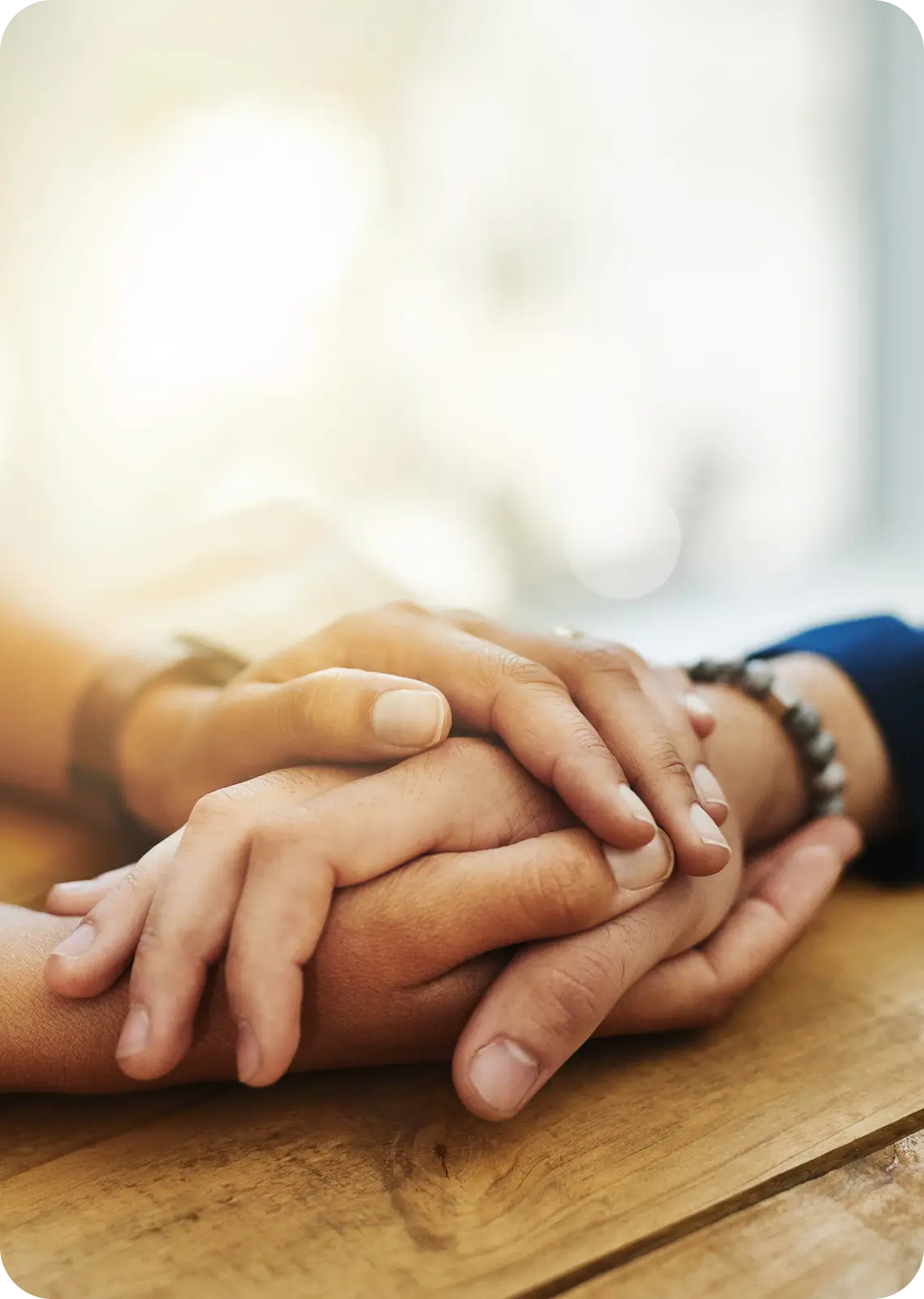 Close-up of two people holding hands gently.