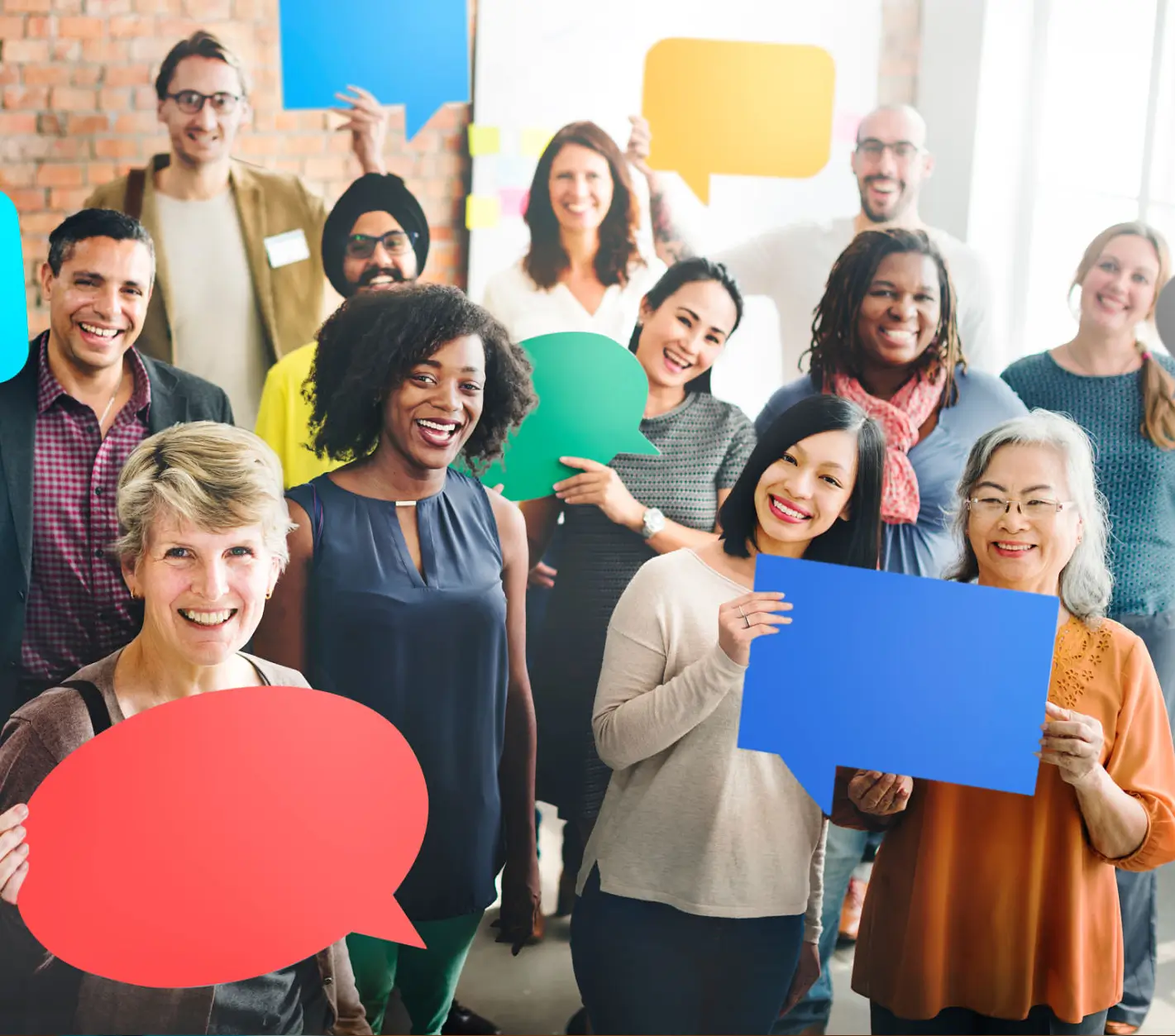 A diverse group of people holding colorful speech bubbles, smiling and engaging.