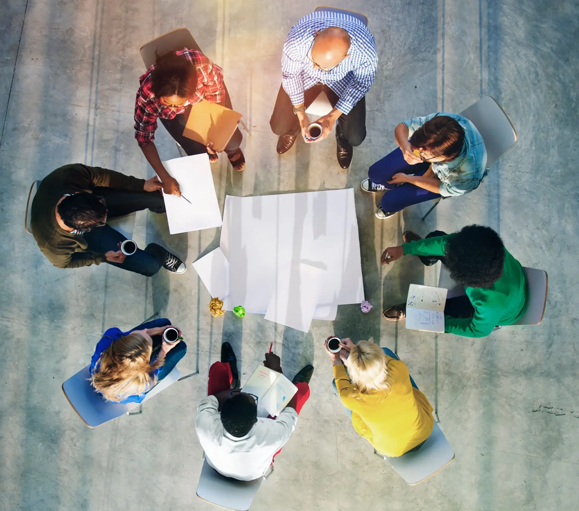 Top view of a diverse group collaborating around a large blueprint.