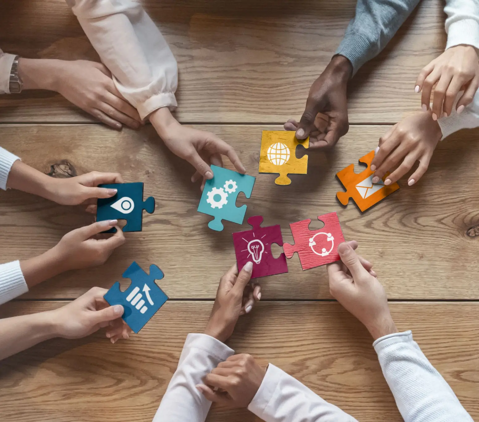 Hands hold colorful puzzle pieces representing teamwork and collaboration.