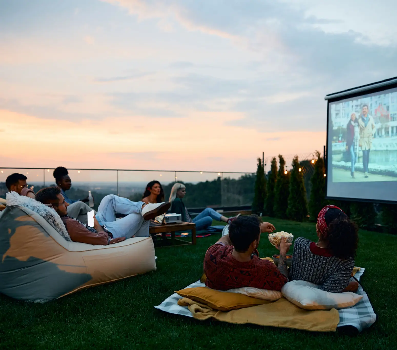 People enjoying an outdoor movie on bean bags at sunset.