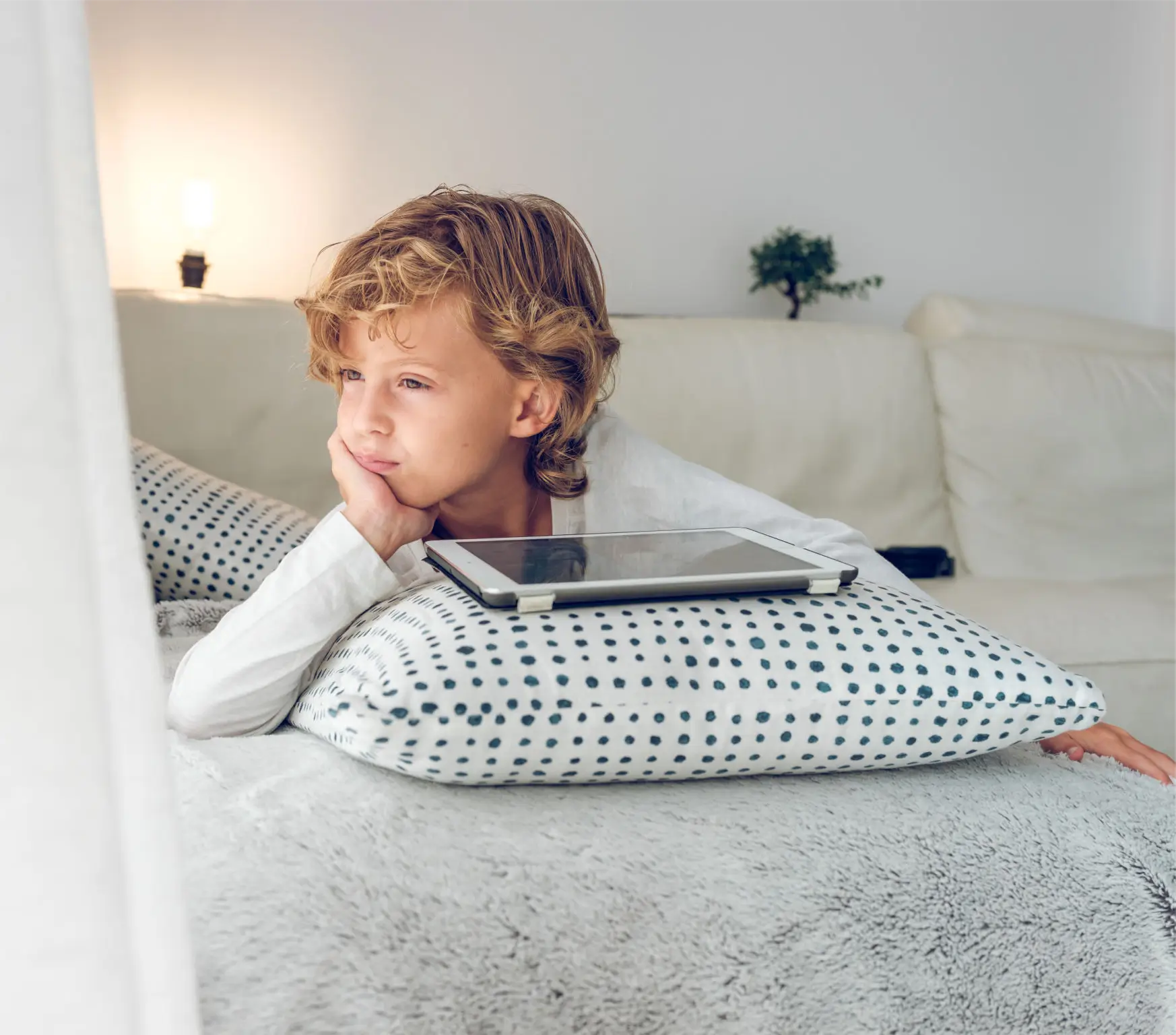 Young boy resting on couch with a thoughtful expression.