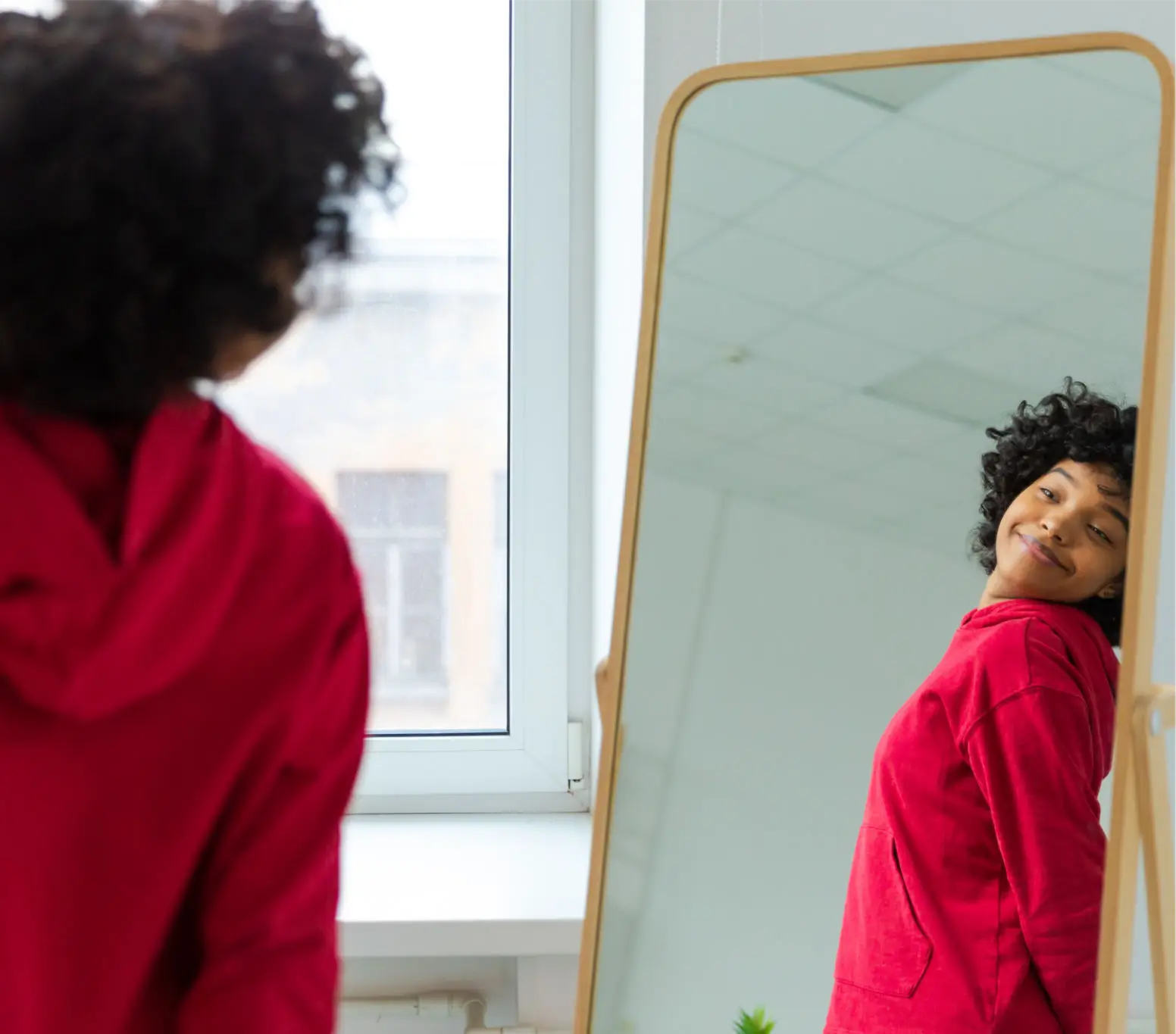A person in a red robe looking at their reflection in a mirror.