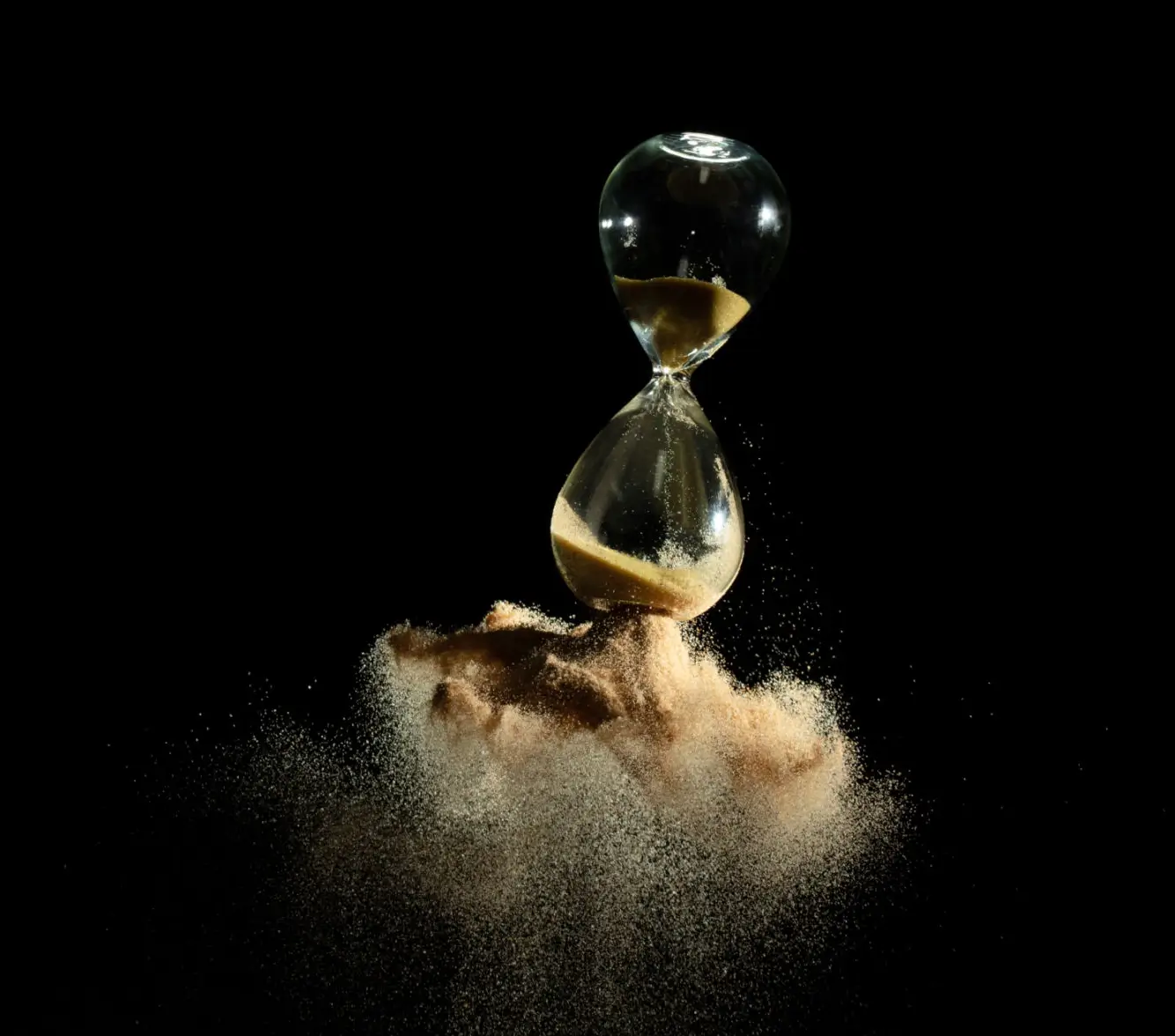 An hourglass releasing golden sand into a cloud of dust.